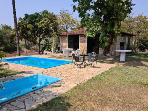 een achtertuin met een blauw zwembad en een tafel en stoelen bij Sitio para Fim de Semana ! 1h de BH in Esmeraldas