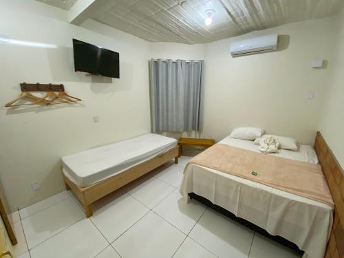 a bedroom with two beds and a flat screen tv at Pousada Segredo in Bonito