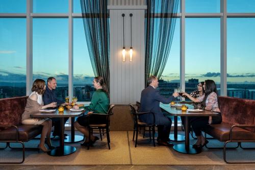 a group of people sitting at tables in a restaurant with windows at Four Points by Sheraton Auckland in Auckland