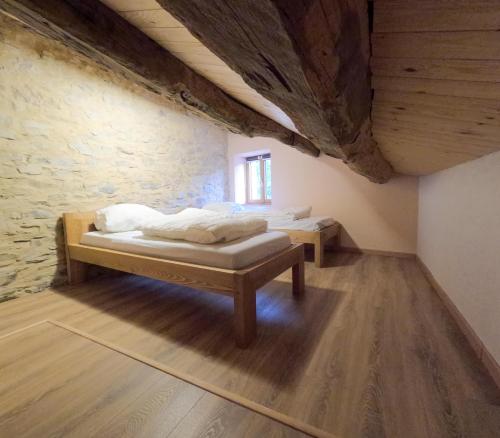 a bedroom with two beds and a stone wall at Gîtes du Pont de Calmel in Rieussec