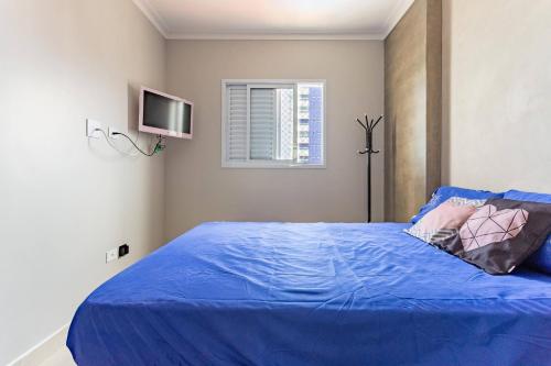 ein Schlafzimmer mit einem blauen Bett und einem TV in der Unterkunft Apartamento na Praia Grande II - Pé na Areia in Praia Grande