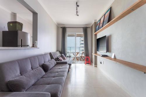 ein Wohnzimmer mit einem Sofa und einem TV in der Unterkunft Apartamento na Praia Grande II - Pé na Areia in Praia Grande