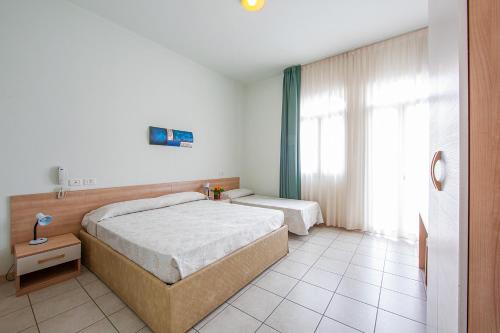 a bedroom with two beds and a window at Hotel Ginevra in Lido di Jesolo