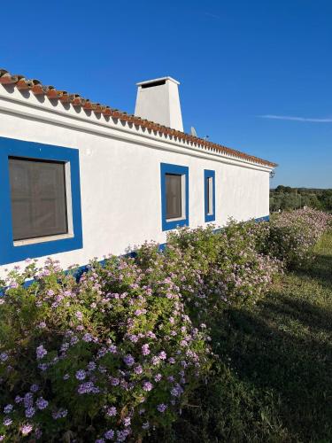 a white house with blue windows and flowers at Casa de Campo, Quinta do Funchal in Arraiolos