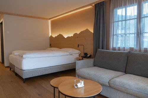 a hotel room with a bed and a couch at Hotel Alpenland in Gstaad