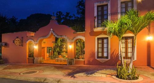 a large orange house with a palm tree in front of it at Hacienda Kamelot. (previously named Hacienda San Miguel) in Guadalajara