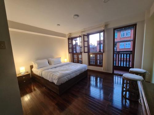 a bedroom with a bed and two large windows at Dalucha Heritage Home in Pātan