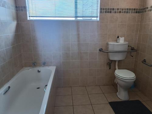 a bathroom with a tub and a toilet and a sink at Orchard Guesthouse in Bloemfontein