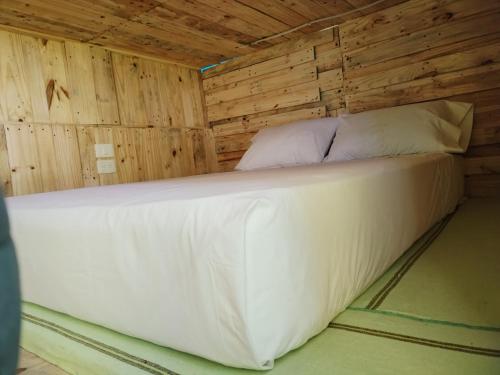 Cama en habitación con pared de madera en Hostel Tropico 20 PDC, en Playa del Carmen