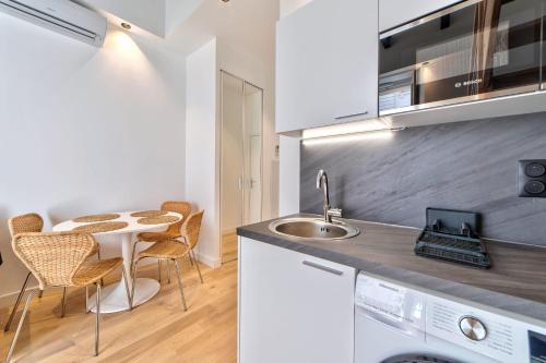 une cuisine avec un évier et une table avec des chaises dans l'établissement Appartement Croisette Cannes centre, à Cannes