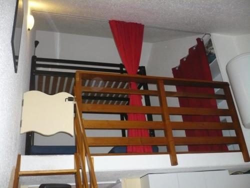 Ce lit superposé se trouve dans un dortoir doté d'un rideau rouge. dans l'établissement Azur Sancy Skis aux pieds, à Le Mont-Dore