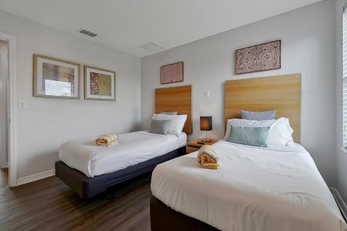 Encantada Resort Vacation Townhomes by IDILIQ في كيسيمي: سريرين في غرفة بجدران بيضاء
