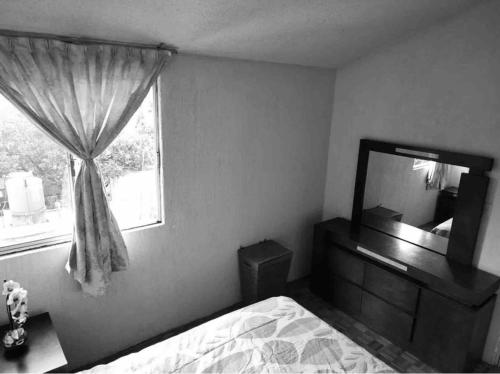 Schlafzimmer mit einem Bett, einem Spiegel und einem Fenster in der Unterkunft DEPARTAMENTO CON VISTA HERMOSA A 5 MIN DE SIX FLAGS in Mexiko-Stadt