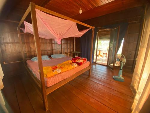 a bedroom with a canopy bed in a house at Banlung Hill Top House &Trekking in Phumĭ Pôy