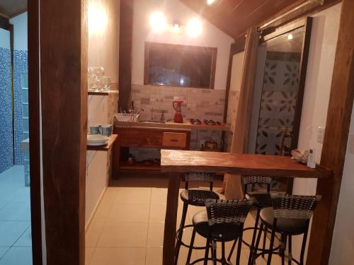 a kitchen with a bar with stools and a television at Pousada Casa Na Bolom in Barra Grande
