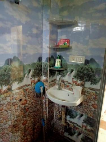 ein Badezimmer mit einem Waschbecken und eine Wand mit einem Gemälde in der Unterkunft home sweet home in Bhopal