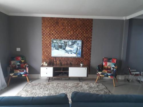 a living room with a couch and a tv on a wall at Casa na melhor praia do Recreio dos Bandeirantes in Rio de Janeiro