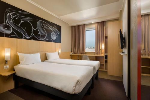a hotel room with two beds and a desk at ibis Kyiv Railway Station in Kyiv