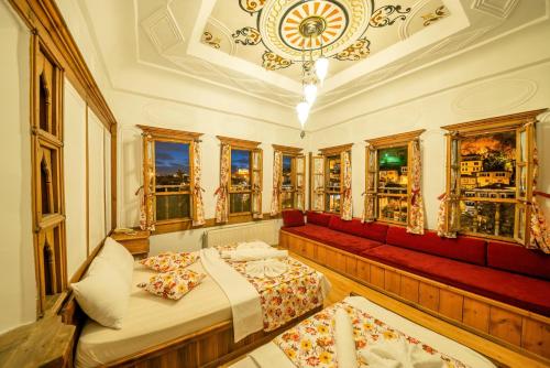een kamer met een bed, een rode bank en ramen bij Cesmeli Konak Corner in Safranbolu