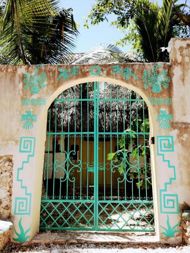 an entrance gate to a building with a green gate at Hotel y Museo Aldea Maya Toktli Orígenes - Casa Maya Melipona - Alberca, Wifi Starlink, Tour Museo in Izamal