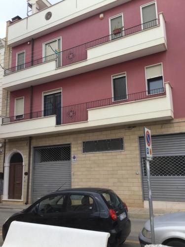a black car parked in front of a pink building at Dimora Gentile in Conversano
