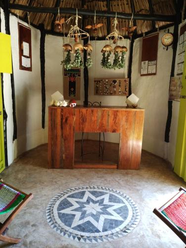 a room with a wooden table and a rug on the floor at Hotel y Museo Aldea Maya Toktli Orígenes - Casa Maya Melipona - Alberca, Wifi Starlink, Tour Museo in Izamal