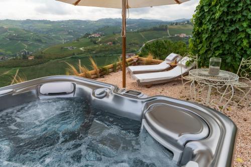 a hot tub with an umbrella and a table and chairs at Cascina Portinale 8 in Alba