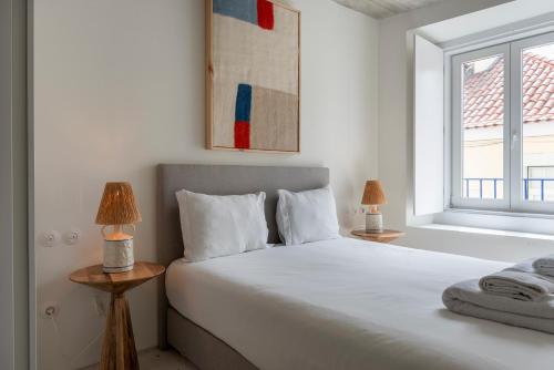 a white bedroom with a bed and a window at A Escada - Alfama Design Apartments in Lisbon