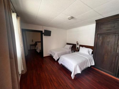 a bedroom with two beds and a wooden floor at Hotel El Morlaco in Cuenca