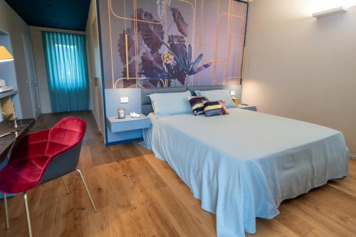 a bedroom with a large bed and a red chair at Cascina Portinale 8 in Alba