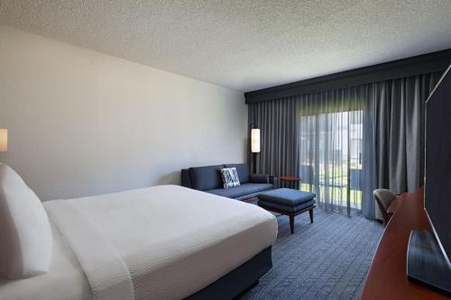 a hotel room with a bed and a chair and a window at Courtyard Fort Worth University Drive in Fort Worth