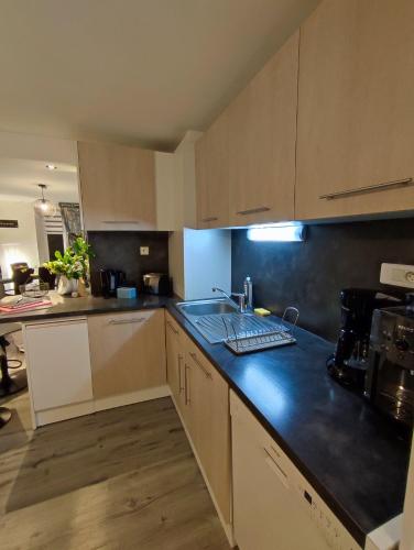 a kitchen with white cabinets and a black counter top at Gîte cosy avec avec jardin et parking privatifs - Hautes Vosges in Saint-Amé