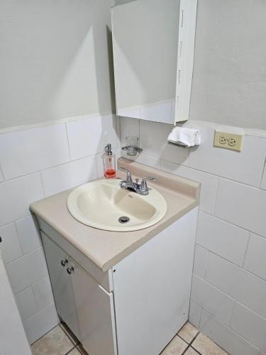 a white bathroom with a sink and a mirror at Jardín de la Nonna #1 in San Pedro Sula