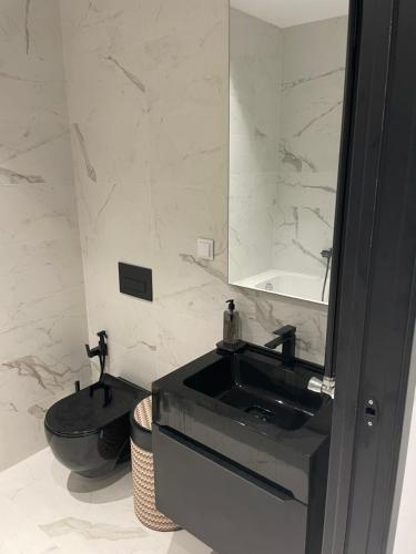 W łazience znajduje się czarna umywalka i lustro. w obiekcie Tunis Résidence california w mieście Le Kram