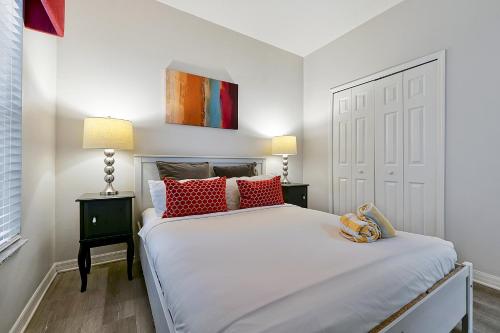 a bedroom with a large white bed with red pillows at Encantada Resort Vacation Townhomes by IDILIQ in Kissimmee