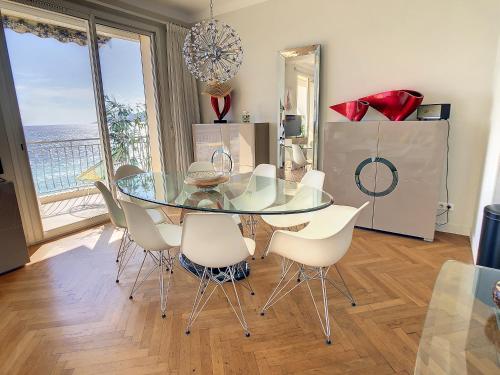 une salle à manger avec une table en verre et des chaises blanches dans l'établissement Beach Penthouse with unique rooftop terrace 301, à Cannes
