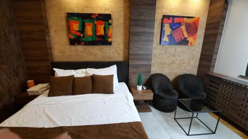 a bedroom with a bed and two chairs at Stan na Dan Apartman D Lux Jacuzzi in Kragujevac