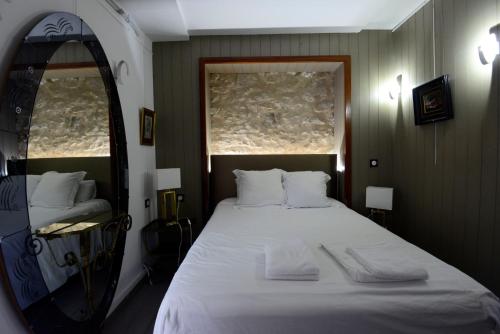 a bedroom with a large white bed with a mirror at Hotel de la muraille de sens in Sens