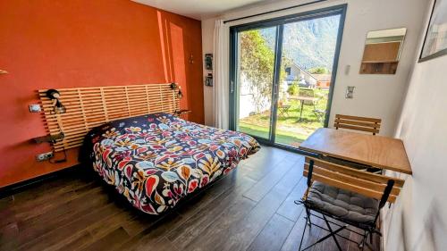a bedroom with a bed and a desk and a window at Studio à la campagne au bout du lac d'Annecy in Doussard