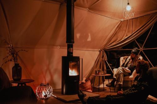a group of people sitting in a tent with a fire at Teapot Lane Glamping - Adults only in Sligo