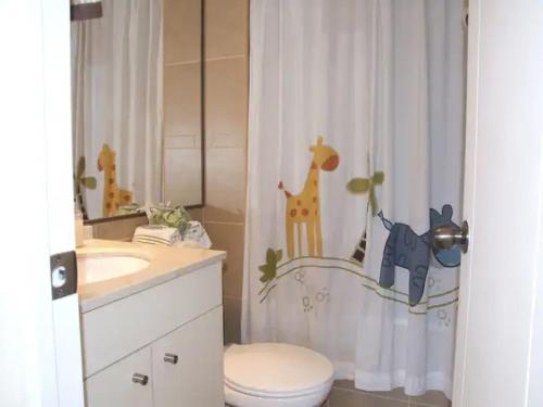 baño con cortina de ducha con jirafas y aseo en bellavista Departamento Amoblado, en Santiago