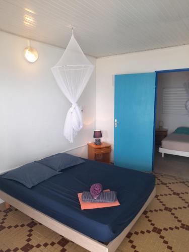 a bedroom with a bed with a blue bedspread at TI PARADIS DE l'ANSE FIGUIER VILLA voir site vacances en martinique in Rivière-Pilote