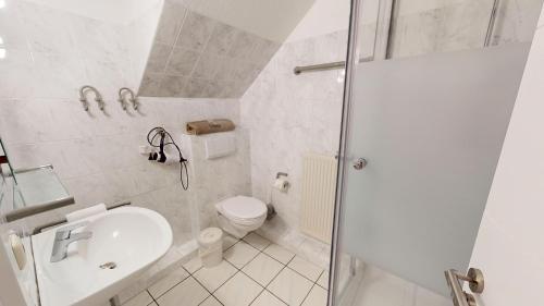 ein weißes Bad mit einem WC und einem Waschbecken in der Unterkunft Gilde-Residenz App. 5 in Grömitz