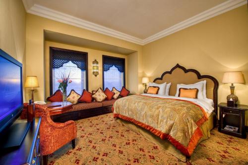 a bedroom with a large bed and a couch at Djibouti Palace Kempinski in Djibouti
