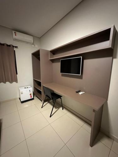 a room with a desk with a tv on a wall at Shafira Hotel in Limeira