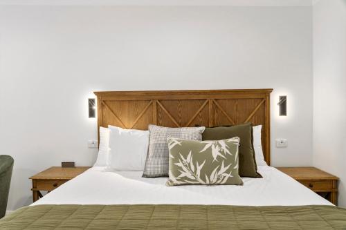 una camera da letto con letto, lenzuola e cuscini bianchi di Beechworth Motor Inn a Beechworth