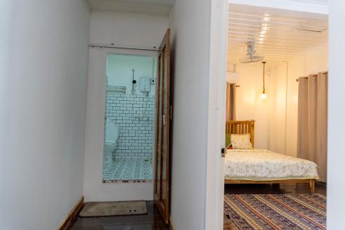 a bedroom with a bed and a glass door leading to a bathroom at La Casa De Jardin in Luang Prabang