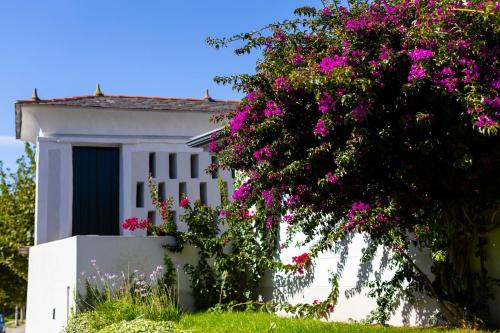 een wit huis met roze bloemen ervoor bij Hotel O Cabazo in Ribadeo