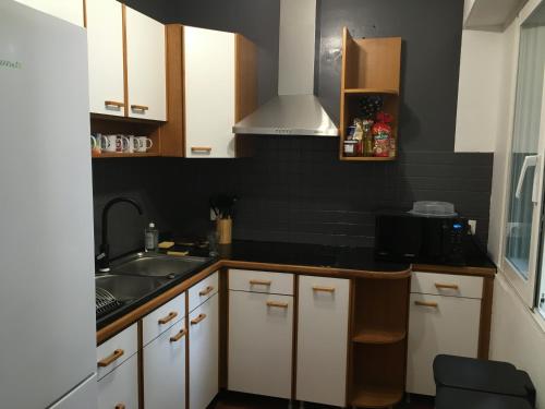 une cuisine avec des armoires blanches et un évier dans l'établissement Banane & C avec sa terrasse, à Lorient