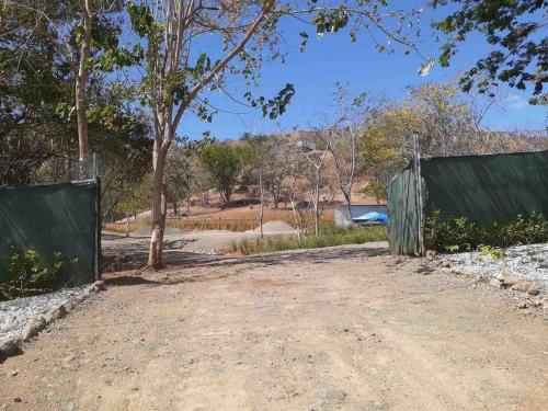 a dirt road with a fence and a tree at Glamping en Playa Potrero in Potrero